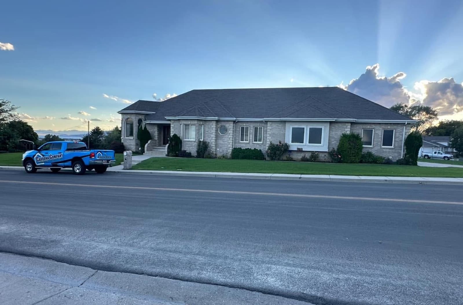 Completed roof on a long stone Southern Utah home at golden hour with the Cardona Company truck out front