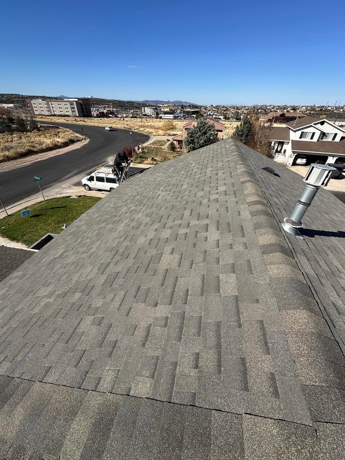 On-roof view down a gray shingle roof with the Cedar City cityscape and Southern Utah desert stretching to the horizon