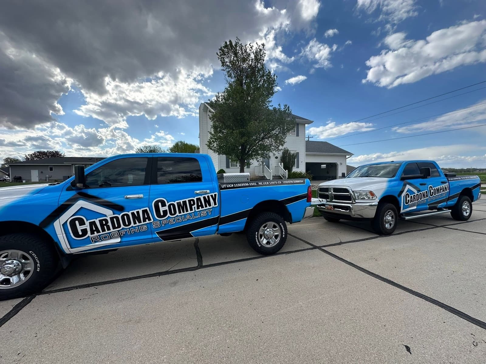 Two Cardona Company branded roofing trucks parked at a job site ready to work